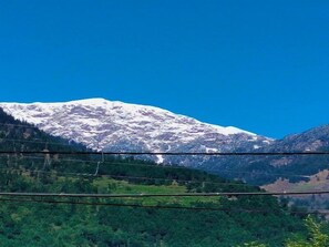 Une montagne aux sommets enneigés, sous un ciel bleu et dégagé.