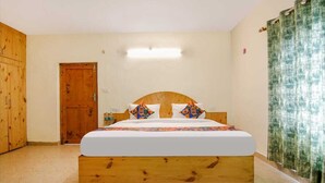 A bedroom with a wooden headboard bed, a door, and a curtain. - Arigato Cottage (Manali)