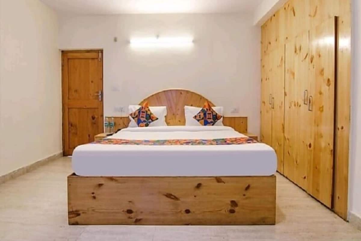 Une chambre à coucher avec une tête de lit en bois, un lit agrémenté de coussins colorés et une armoire en bois.