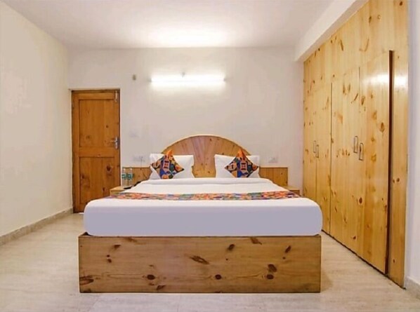 Une chambre à coucher avec une tête de lit en bois, un lit agrémenté de coussins colorés et une armoire en bois.