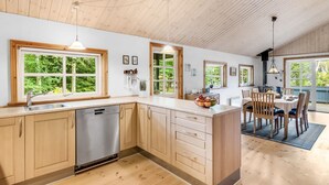 A modern kitchen with wooden cabinets, a dishwasher, and a dining area with a table and chairs. - "Femme" by Interhome (Blåvand)