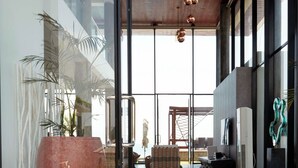 Amplio espacio interior con diseño moderno, que cuenta con un gran ventanal, techo de madera y una zona de estar con sofá y mesa.