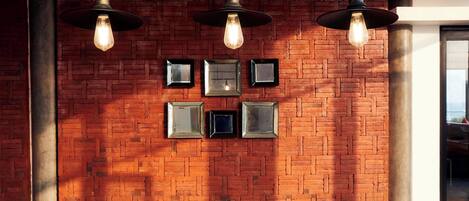 A brick wall with framed pictures and hanging pendant lights.