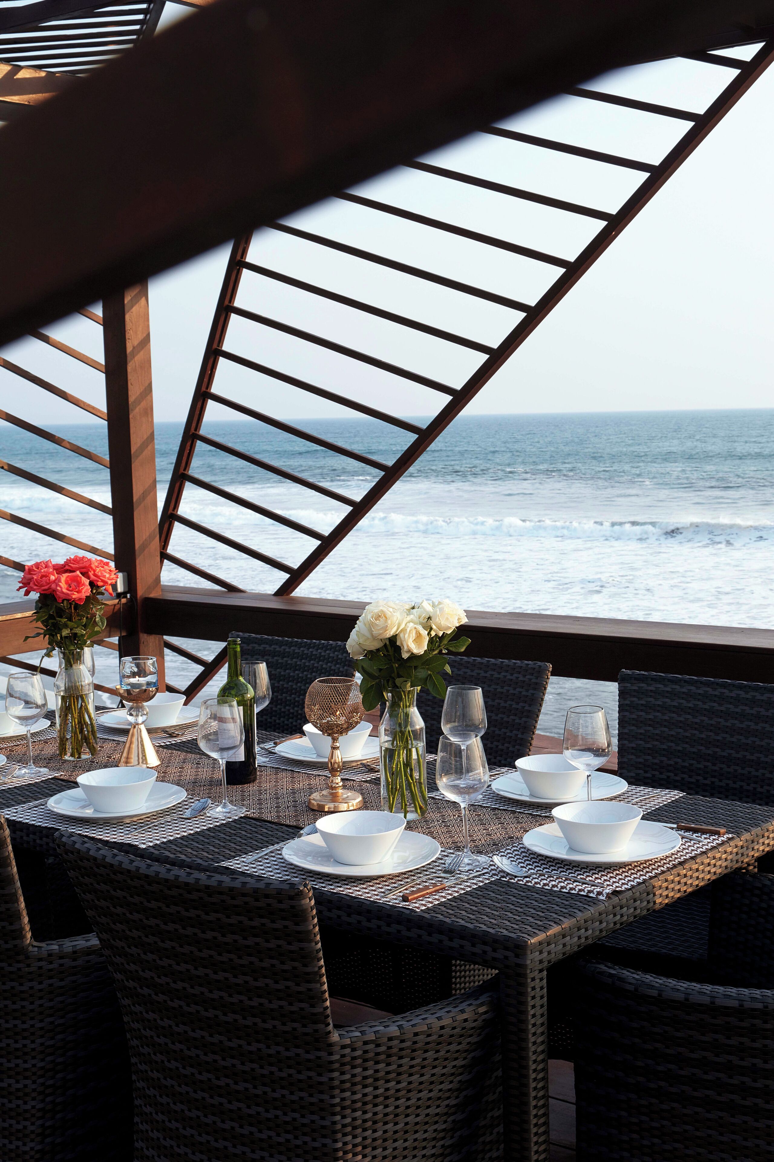 A dining table set for two with a view of the ocean.