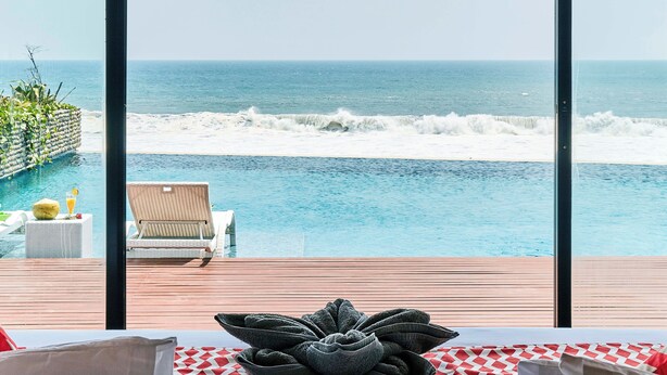 Una habitación con un amplio ventanal con vistas a una piscina y el océano.