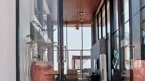 Una entrada moderna de edificio con puertas de cristal, techo de madera y vista al interior.