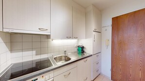 A modern kitchen with white cabinets, a stainless steel sink, and a built-in stove. - Well-kept holiday apartament house in a prime location in St. (St. Moritz)
