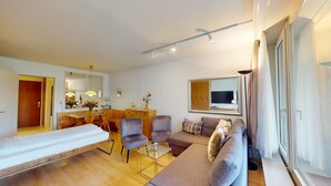 A modern living room with a sofa, armchairs, a dining table, and a TV. - Well-kept holiday apartament house in a prime location in St. (St. Moritz)