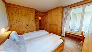 A wooden bedroom with a large bed, wooden wardrobe, and a window with curtains. - Well-kept holiday apartament house in a prime location in St. (St. Moritz)