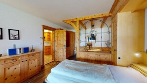 A wooden room with a bed, a dresser, and a mirror with a decorative frame. - Well-kept holiday apartament house in a prime location in St. (St. Moritz)