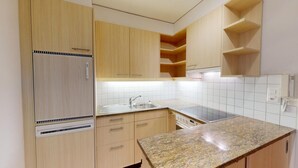 A modern kitchen with light wood cabinets, a granite countertop, a built-in oven, and a stainless steel sink. - Well-kept holiday apartament house in a prime location in St. (St. Moritz)