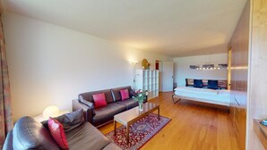 A modern living room with a sofa, coffee table, and a dining area with chairs and a table. - Well-kept holiday apartament house in a prime location in St. (St. Moritz)