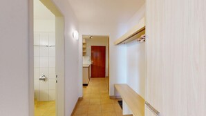 A narrow hallway with a wooden bench, a tiled floor, and a door leading to a kitchen area. - Well-kept holiday apartament house in a prime location in St. (St. Moritz)