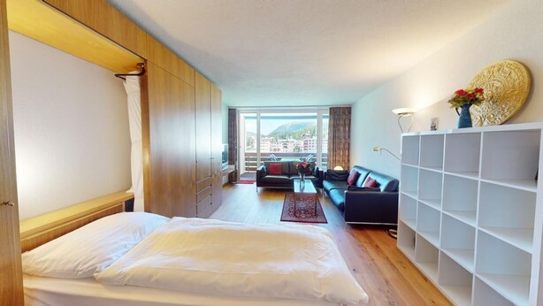 A hotel room with a bed, a sofa, a dining table, and a view of the city. - Well-kept holiday apartament house in a prime location in St. (St. Moritz)