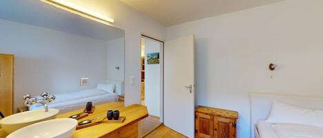 A bedroom with a bed, a wooden cabinet, a bedside table, and a large mirror.