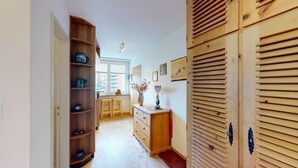 A hallway with wooden shelves, a wooden cabinet, and a window with a view of buildings.