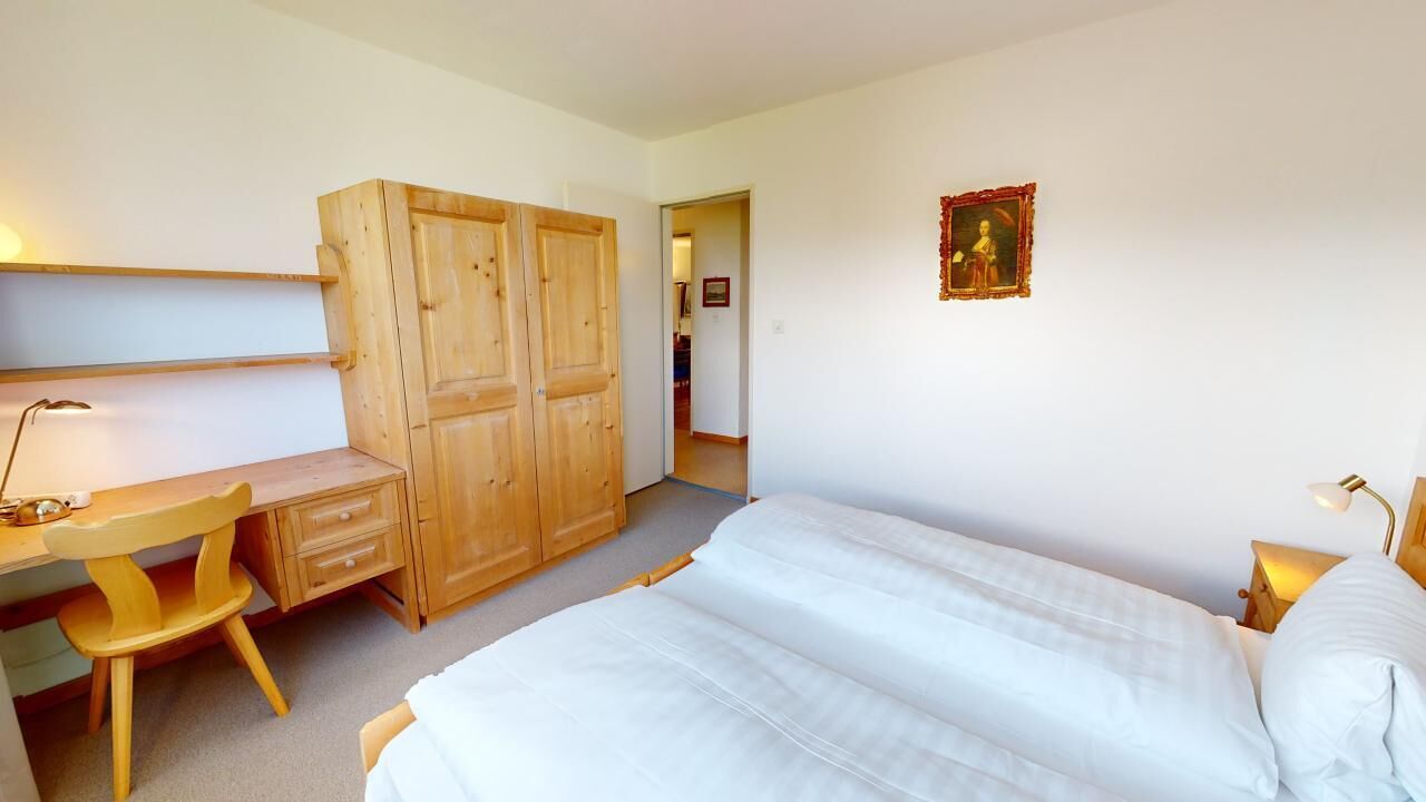 A bedroom with a bed, a desk with a chair, and a wardrobe.