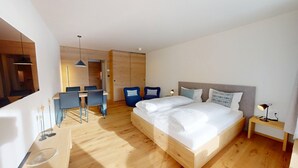 A modern hotel room with a wooden floor, a bed with white bedding, a desk with two chairs, and a small bedside table with a lamp. - Well-kept holiday apartament house in a prime location in St. (St. Moritz)