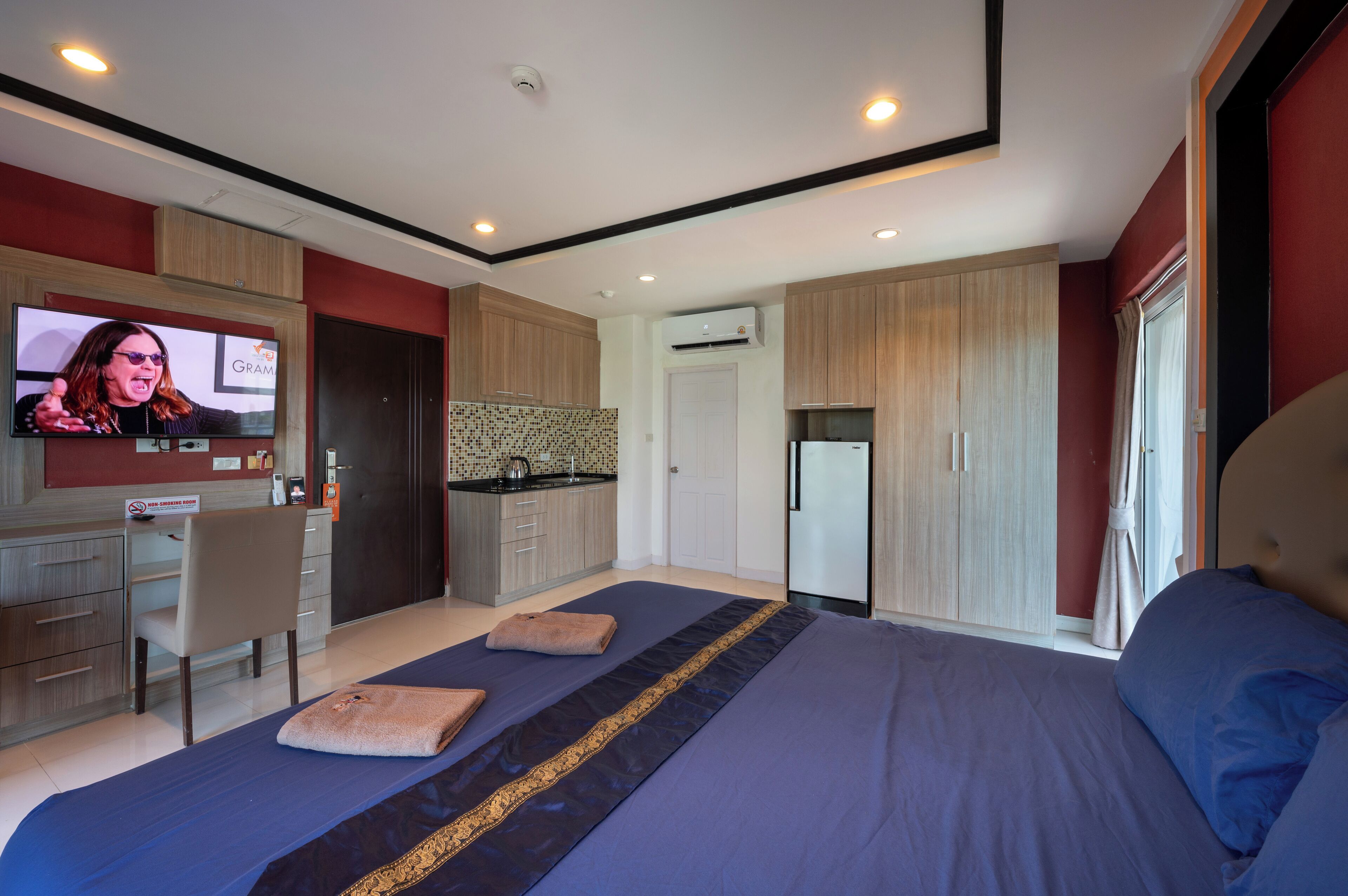 A modern bedroom with a large bed, a desk, and a television.