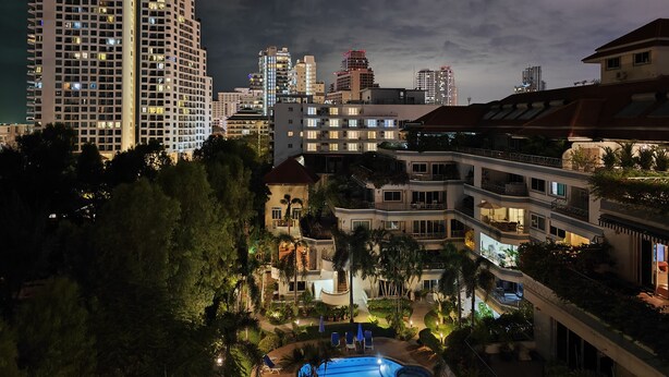 A multi-story hotel with balconies, a swimming pool, and a city skyline in the background. - New Nordic VIP 6 Kristine (Pattaya)
