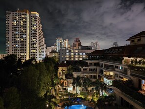 Un hôtel à plusieurs étages doté de balcons, d’une piscine et offrant une vue sur le panorama urbain en arrière-plan.