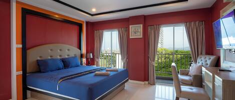 A modern hotel room with a large bed, a desk, and a view of the outdoors.