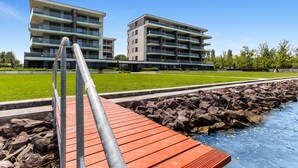 A modern building with multiple balconies and a well-maintained lawn. - Lakefront Elegant Condo Lela (Balatonlelle)