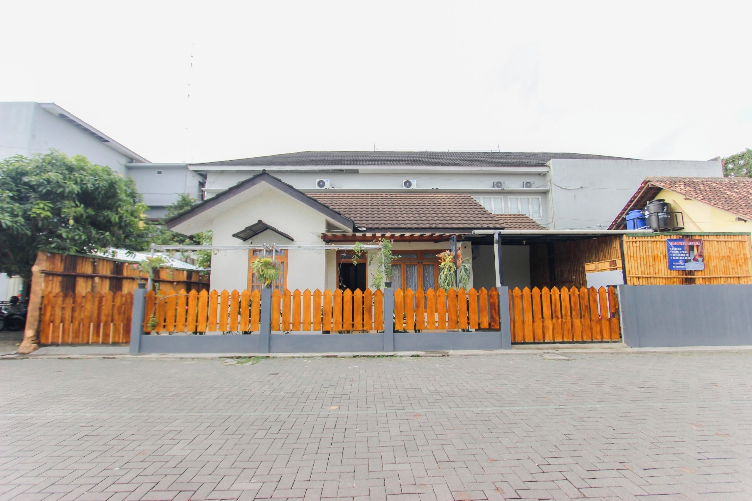 A building with a tiled roof, a wooden fence, and a paved entrance area.