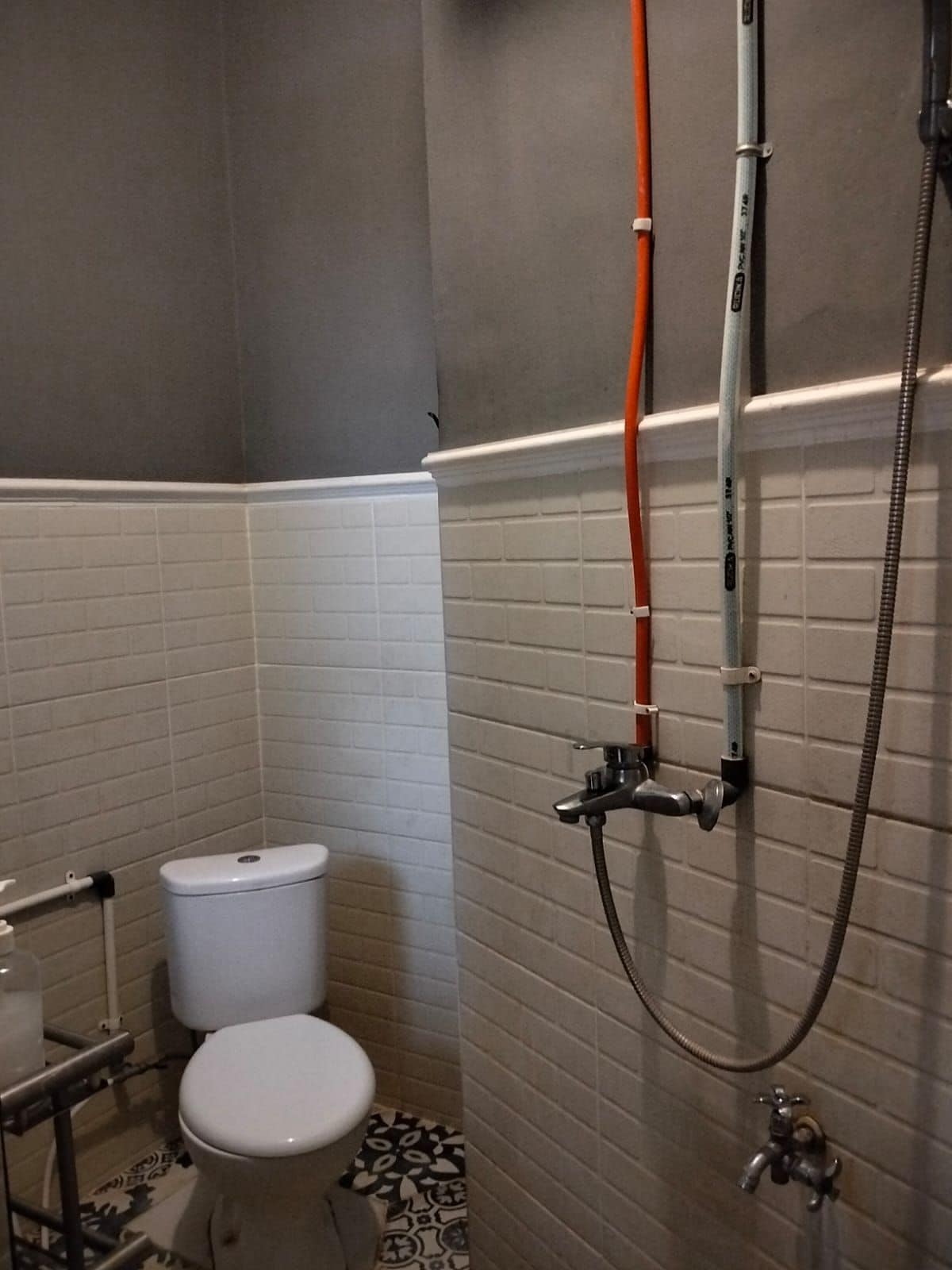 A bathroom with a toilet, a shower, and a hand dryer.