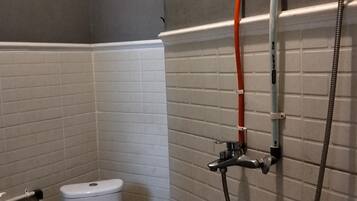 A bathroom with a toilet, a shower, and a hand dryer.