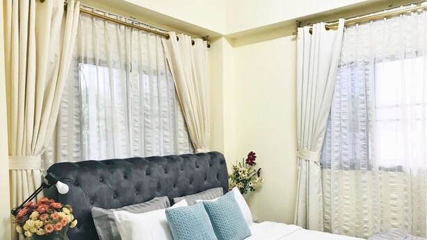 A bedroom with a tufted headboard, white bedding, and a vase of flowers. - Cozy 1-bedroom with WiFi and AC in delightful Chiang Mai, Self-check-in, Parking (Chang Wat Chiang Mai)