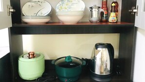 A kitchen cabinet with a microwave, a kettle, a pot, and various kitchen utensils. - Cozy 1-bedroom with WiFi and AC in delightful Chiang Mai, Self-check-in, Parking (Chang Wat Chiang Mai)