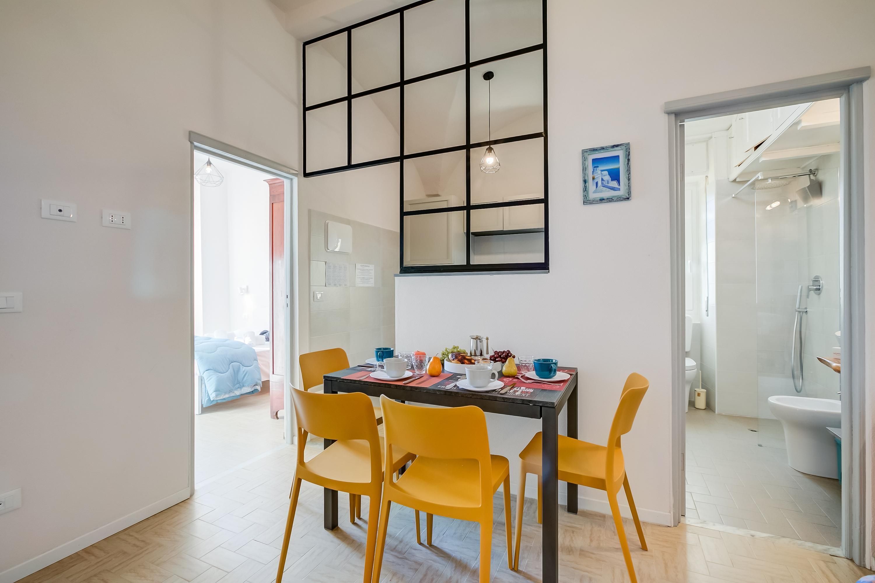A dining area with a table set for four, yellow chairs, and a large window with a grid design.