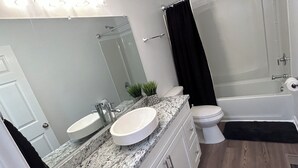 A modern bathroom with a white sink, a mirror, a toilet, and a bathtub. - Luxury Apartment In Charlotte  (Charlotte)