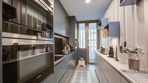 Een moderne keuken met roestvrijstalen apparatuur, een inbouwoven en diverse keukengerei en pannen op het aanrecht.