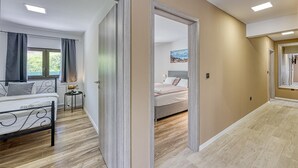 A modern hotel room with a bed, bedside table, and a view of a mountain landscape through the window. - Urban Oasis With Terrace And Parking (Zagreb)