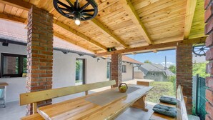 An outdoor patio with wooden benches and a table, brick pillars, and a view of neighboring houses. - Urban Oasis With Terrace And Parking (Zagreb)