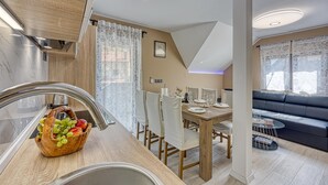 A modern kitchen with a wooden countertop, a fruit basket, and a dining area with a table and chairs. - Urban Oasis With Terrace And Parking (Zagreb)