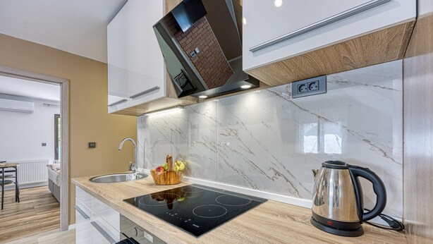 A modern kitchen with a built-in stove, a kettle, and a fruit basket on the counter. - Urban Oasis With Terrace And Parking (Zagreb)