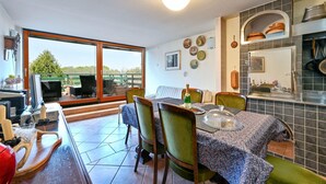 Un comedor con una mesa dispuesta para cuatro personas, sillas, una cubierta de vidrio tipo cúpula y una botella de champán.
