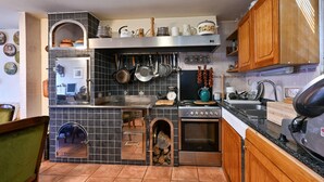 Una cocina con estufa, horno y diversos utensilios.