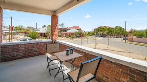 A balcony with a brick wall, a table, and two chairs. - Built in 1915, this quaint historic El Paso home surprises you with its modern updates and decor. The location could not be more convenient as it is steps away from the bus stop, one block from BCycle Bike Share rental, and 4 blocks from UTEP. Take a (El Paso)