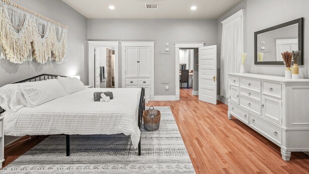 A bedroom with a bed, dresser, and a macrame wall hanging. - Built in 1915, this quaint historic El Paso home surprises you with its modern updates and decor. The location could not be more convenient as it is steps away from the bus stop, one block from BCycle Bike Share rental, and 4 blocks from UTEP. Take a (El Paso)