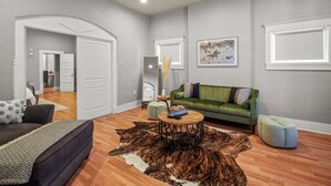 A modern living room with a green sofa, a round coffee table, and a cowhide rug. - Built in 1915, this quaint historic El Paso home surprises you with its modern updates and decor. The location could not be more convenient as it is steps away from the bus stop, one block from BCycle Bike Share rental, and 4 blocks from UTEP. Take a (El Paso)