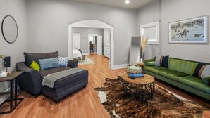 A modern living room with a sofa, ottoman, coffee table, and a rug. - Built in 1915, this quaint historic El Paso home surprises you with its modern updates and decor. The location could not be more convenient as it is steps away from the bus stop, one block from BCycle Bike Share rental, and 4 blocks from UTEP. Take a (El Paso)