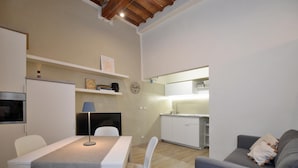Un espacio habitable compacto con comedor, kitchenette y sofá.