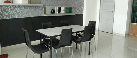 Un comedor moderno con una mesa blanca y sillas negras, un papel tapiz estampado y una puerta al fondo.
