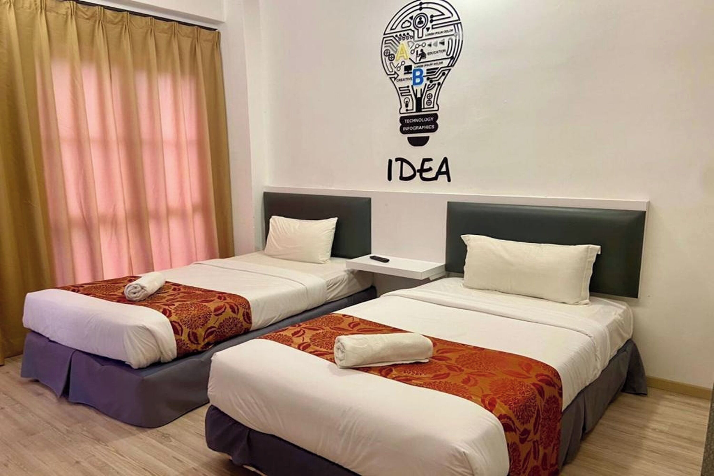 Two single beds with headboards, a wall-mounted light bulb graphic, and the word "IDEA" below it.