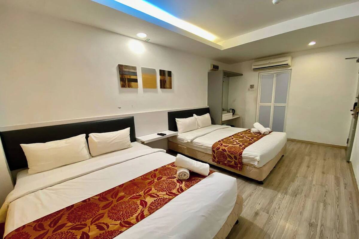 A hotel room with two beds, a mirror, a wardrobe, and a ceiling light.