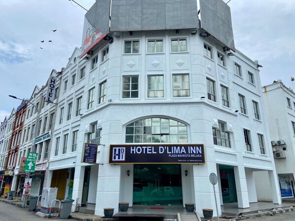 Ein weißes Gebäude mit einem Schild für Hotel D'Lima Inn, das einen großen Bogen und zahlreiche Fenster zeigt.